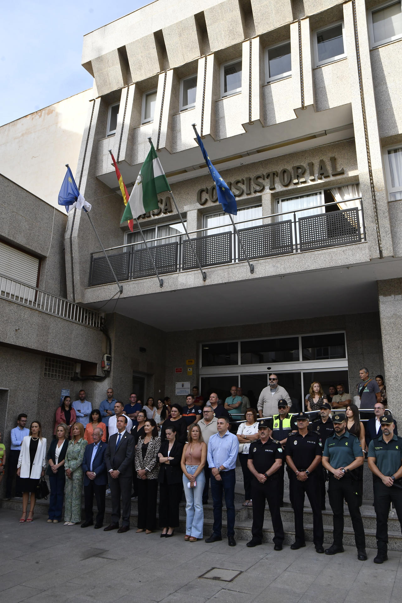 Minuto de silencio convocado por el Ayuntamiento de Roquetas de Mar (Almería) presidido por su alcalde, Gabriel Amat (4i) y al que se han sumado vecinos y otras autoridades en señal de repulsa y condena por el asesinato machista de Mari Nieves, una roquetera de 56 años muerta presuntamente a manos de su pareja, un hombre de 72 años, este martes a las puertas del Consistorio. EFE/Carlos Barba
