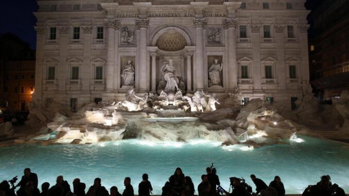 Turistas contemplan la Fontana de Trevi, en Roma, iluminada de noche. EFE/Alessandro Di Meo/Archivo
