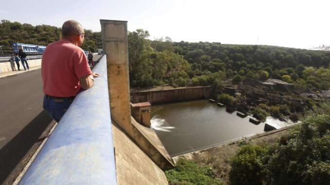 Varias personas observan el estado que presenta la presa derivación de Bembézar en la localidad cordobesa de Hornachuelos que este lunes está desembalsando agua. EFE/Salas
