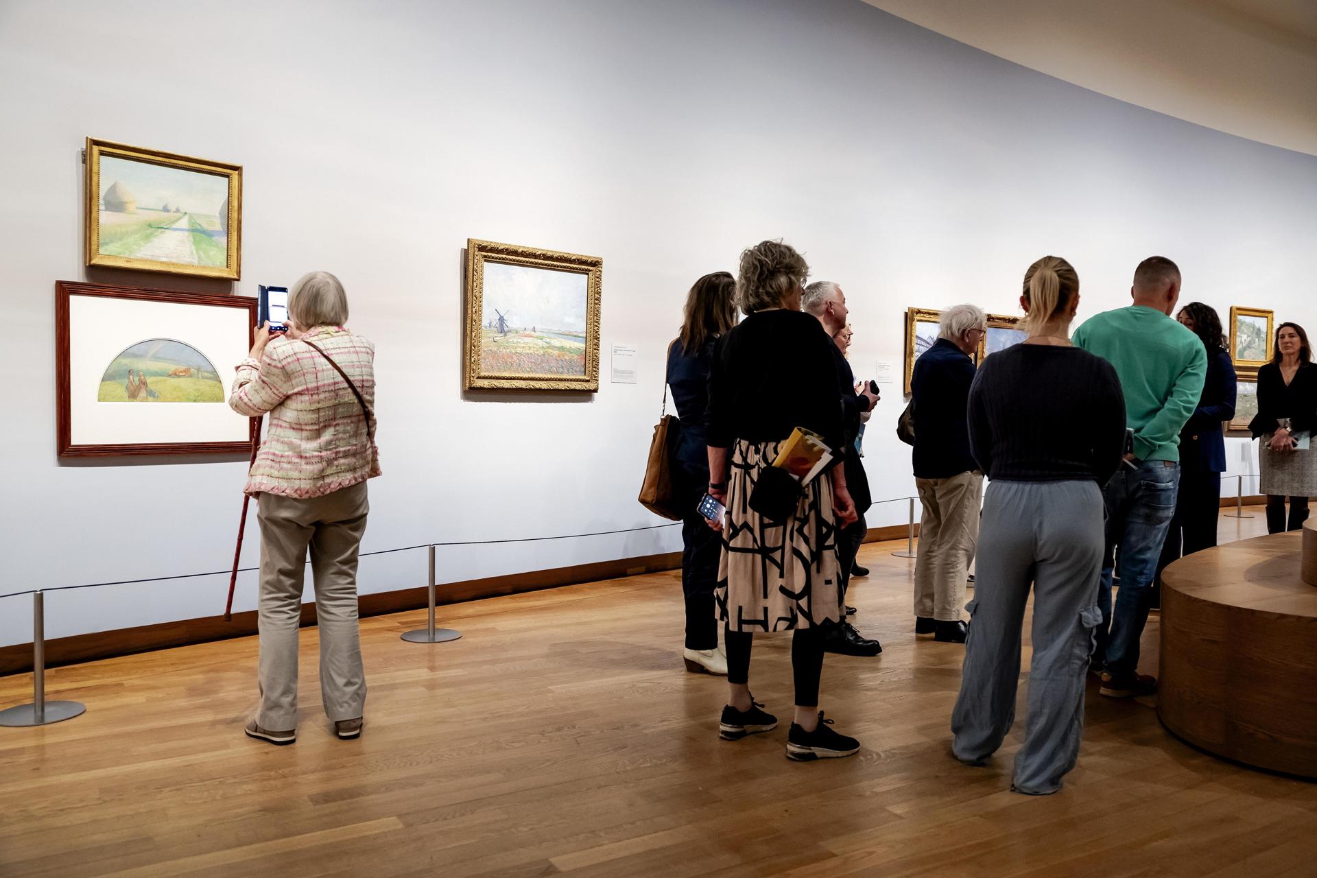 Una mujer contempla las obras 'Paisaje con almiares', de Gustave Caillebotte (arriba), y 'Paisaje con arco iris', de Camille Pissarro (abajo), de la nueva exposición Vive l'impressionnisme! en el Museo Van Gogh de Ámsterdam, el 09 de octubre de 2024. La exposición muestra las mejores obras impresionistas francesas de colecciones holandesas. (Países Bajos; Holanda) EFE/EPA/ROBIN VAN LONKHUIJSEN
