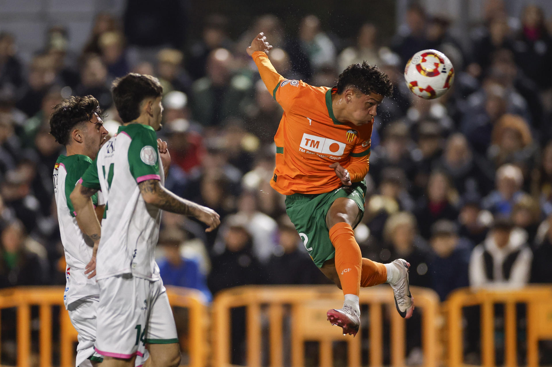 El extremo costarricense del Valencia Warren Madrigal (d) remata un balón durante el encuentro de la Copa del Rey disputado este martes entre el CP Parla Escuela y el Valencia CF en el estadio Las Américas de Madrid. EFE/ Sergio Pérez
