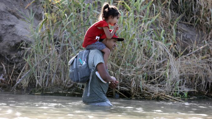 Fotografía de migrantes caminando por el río Grande en Eagle Pass, Texas, EE. UU. EFE/ADAM DAVIS
