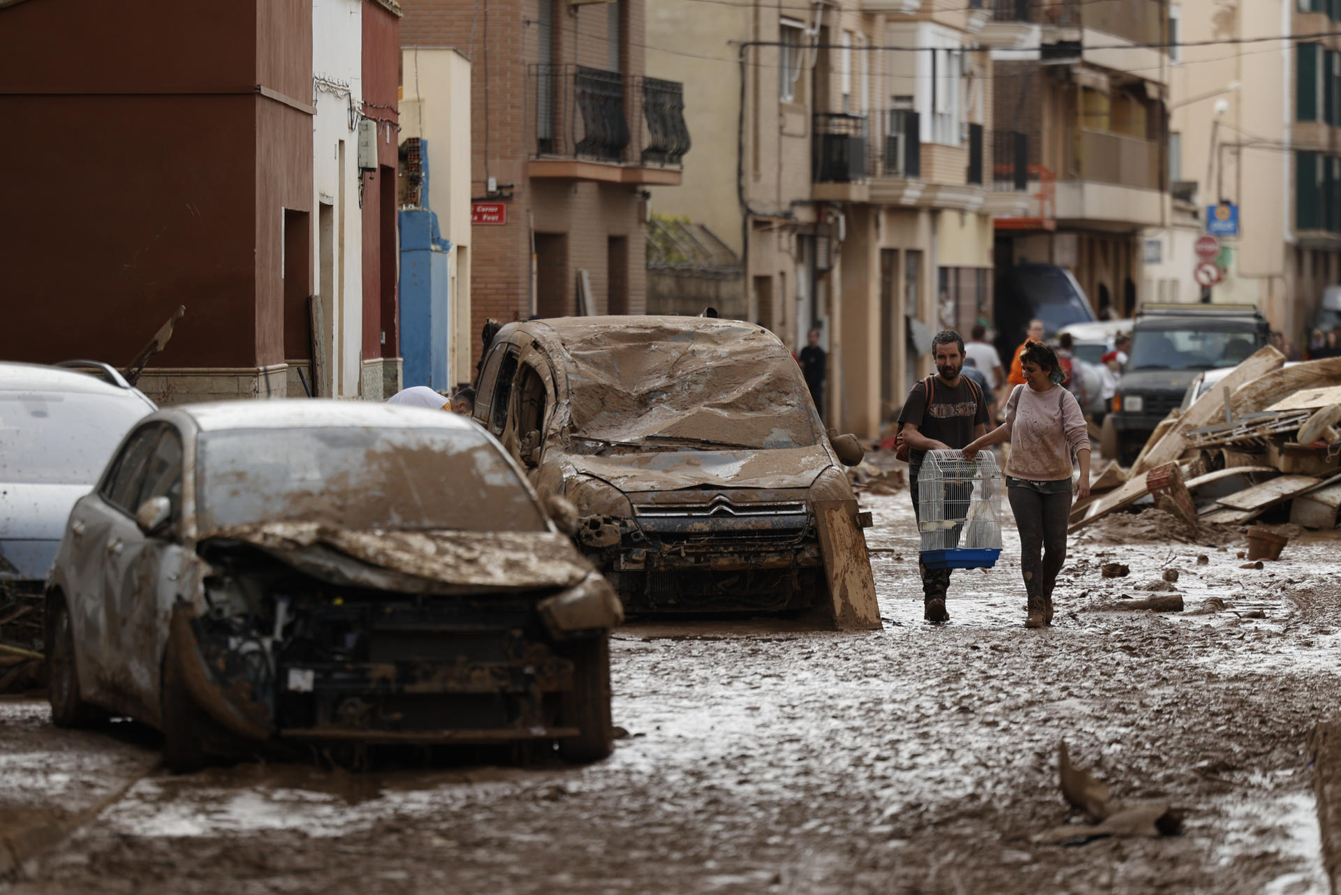 Vecinos de Paiporta trabajan en la limpieza de calles, locales y viviendas de la localidad junto a una montaña de vehículos arrastrados por la corriente, este viernes. Las víctimas mortales en la provincia de Valencia a causa de la devastadora dana ha aumentado este viernes hasta las 205, según el último recuento facilitado por el Centro de Emergencias de la Generalitat Valenciana. EFE/Biel Aliño
