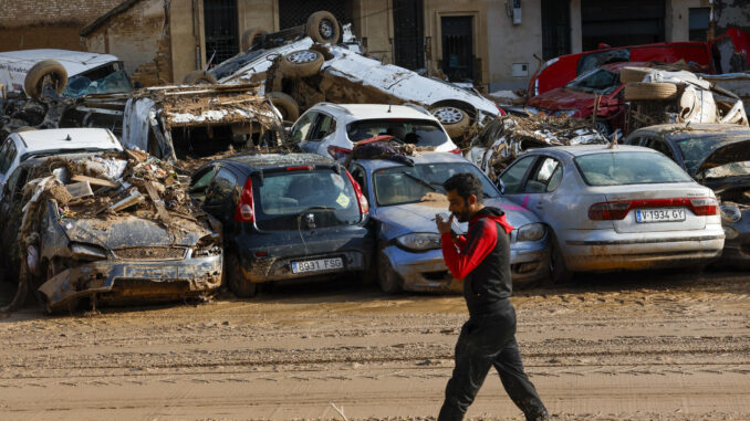 Un hombre camina junto a los coches apilados en Catarroja, Valencia este martes, una de las localidades más afectados por las inundaciones. EFE/ Chema Moya
