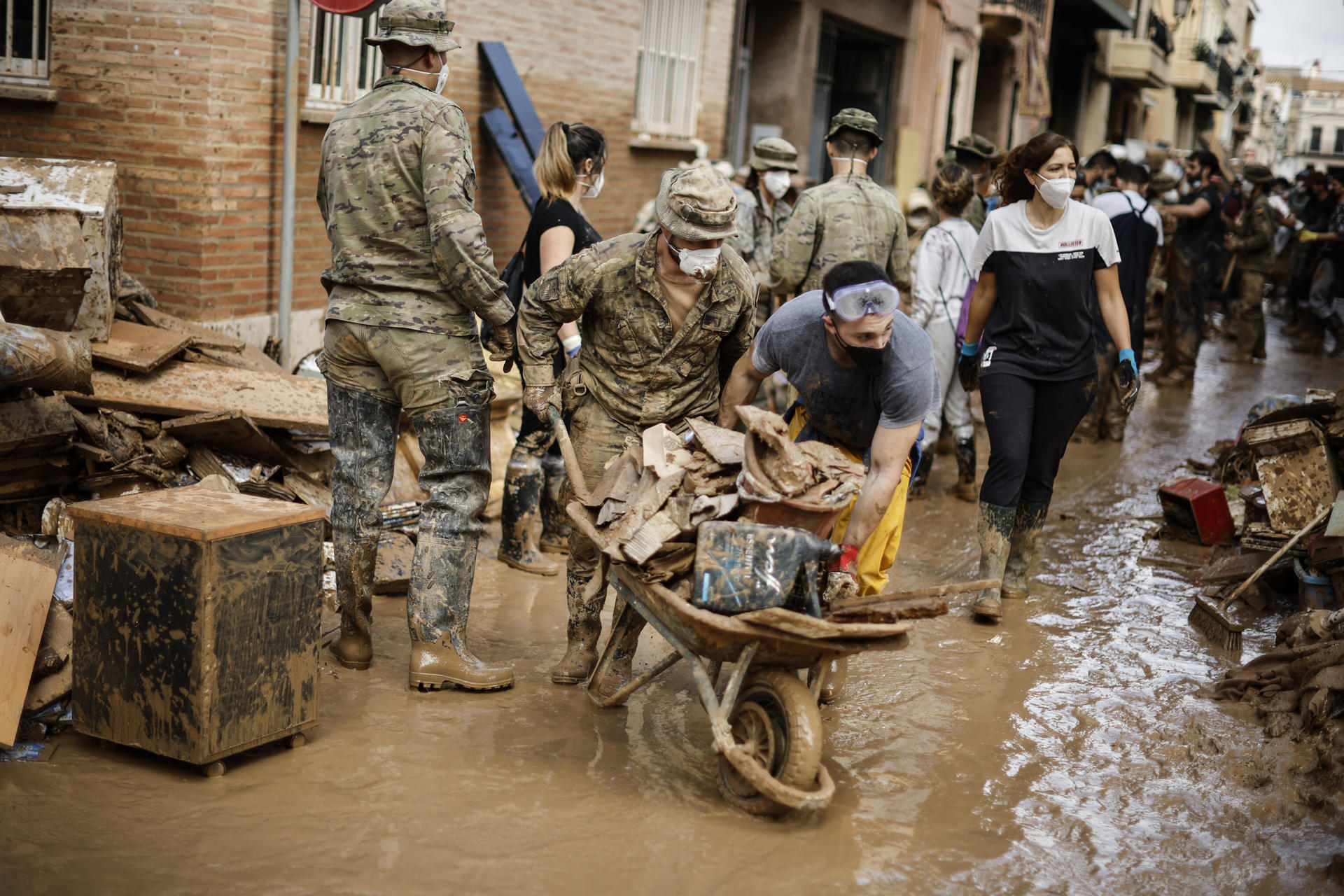 Militares, voluntarios y vecinos trabajan en labores de limpieza y desescombro de Paiporta, este jueves. Los pueblos de Valencia asolados por la dana afrontan el noveno día después de la catástrofe sumidos en un goteo incesante de llegada tanto de ayuda humanitaria como profesional y de maquinaria pesada, para intentar recuperar infraestructuras, colegios, zonas industriales y vías de comunicación mientras continúa la búsqueda de desaparecidos. EFE/ Biel Aliño
