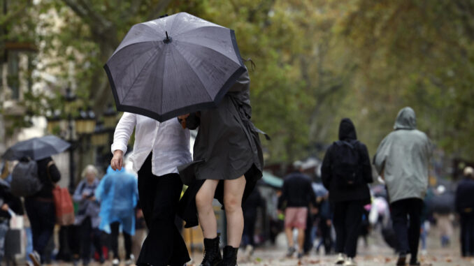 Varias personas se protegen de la lluvia en las Ramblas de Barcelona este lunes. EFE/Toni Albir
