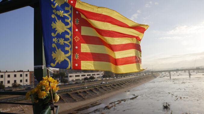 Una bandera de la Comunidad Valenciana junto a un ramillete de flores cuelga de la pasarela que va de Valencia hacia La Torre, este jueves. EFE/Ana Escobar
