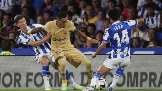 El delantero del FC Barcelona Raphinha (c) trata de controlar un balón ante Take Kubo (d), de la Real Sociedad, durante el partido de Liga de la pasada temporada disputado en el Reale Arena, en San Sebastián. EFE/Javier Etxezarreta
