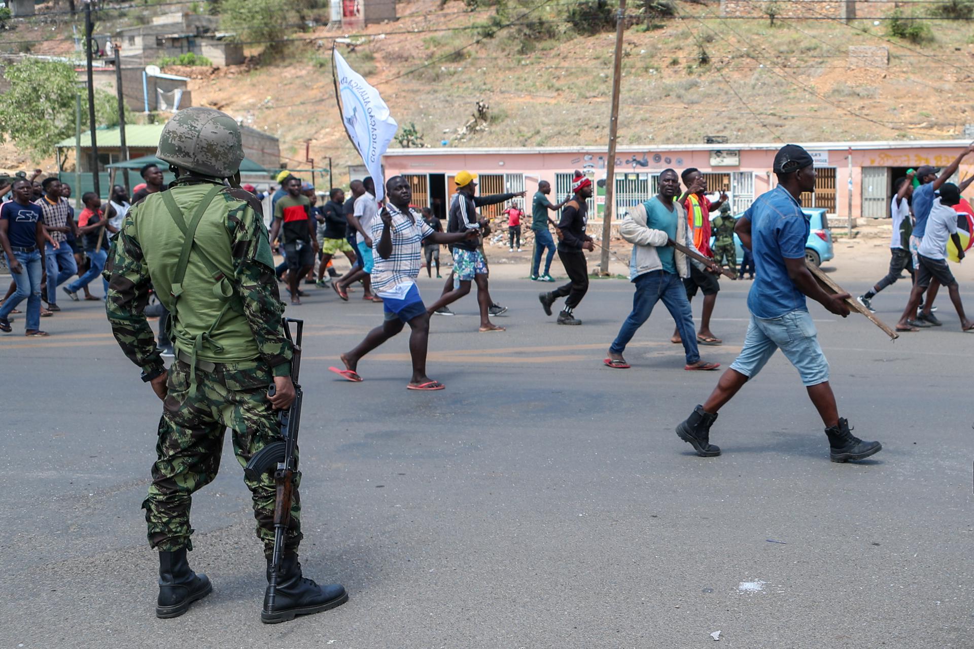 Los partidarios del candidato presidencial Venancio Mondlane caminan junto a personal militar mientras protestan exigiendo la 'restauración de la verdad electoral', bloqueando el tráfico en Ressano Garcia, la principal frontera entre Mozambique y Sudáfrica, fuertemente custodiada por docenas de soldados y policías, Mozambique, 14 de noviembre de 2024. La Comisión Nacional Electoral (CNE) publicó el 24 de octubre los resultados de la tabulación general de las elecciones del 09 de octubre - presidenciales, legislativas y de asambleas provinciales - anunciando la victoria del partido gobernante Frente de Liberación de Mozambique (Frelimo) con 11 escaños más en el parlamento. El candidato presidencial de Frelimo, Daniel Chapo, quien fue elegido con el 70.67 por ciento de los votos, sucederá al presidente saliente, Filipe Nyusi. Estos resultados fueron impugnados por la oposición, que alegó irregularidades. Elecciones, Protestas, Sudáfrica EFE/EPA/LUISA NHANTUMBO
