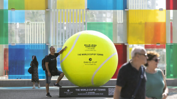 -Una persona se fotografía junto a una de la pelotas de tenis gigantes que se han instalado por el centro de la ciudad dentro de los preparativos para la celebración de las finales de la Copa Billie Jean King, en una foto de archivo. EFE/Daniel Pérez
