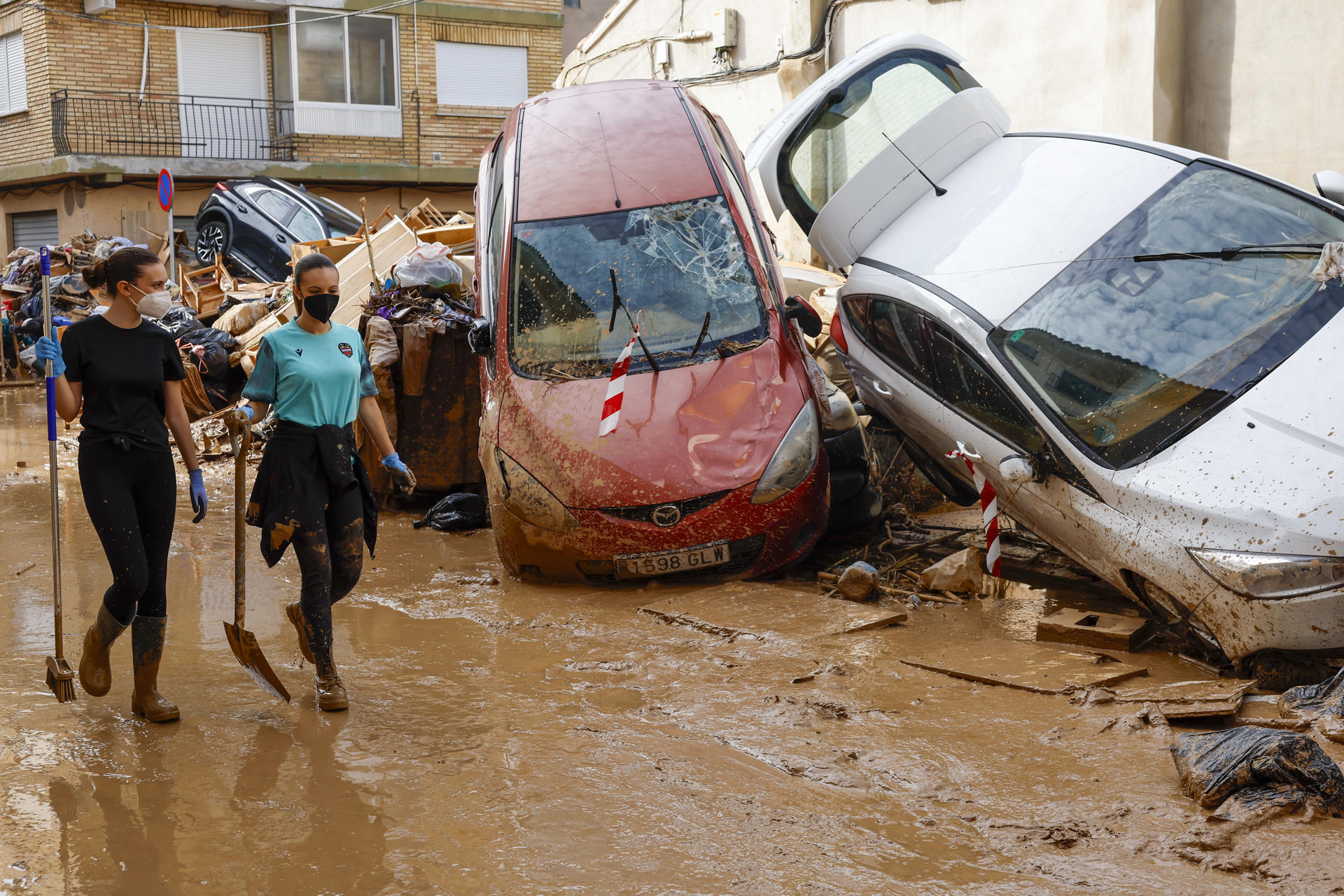 Los vecinos limpian las calles junto a varios coches apilados en Catarroja, Valencia este martes, una de las localidades más afectados por las inundaciones. EFE/ Chema Moya
