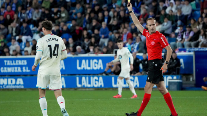 El colegiado Mario Melero López (d) muestra una amonestación a Kike García, del Alavés, durante el partido de LaLiga entre el Alavés y el Real Valladolid. EFE/ ADRIAN RUIZ HIERRO
