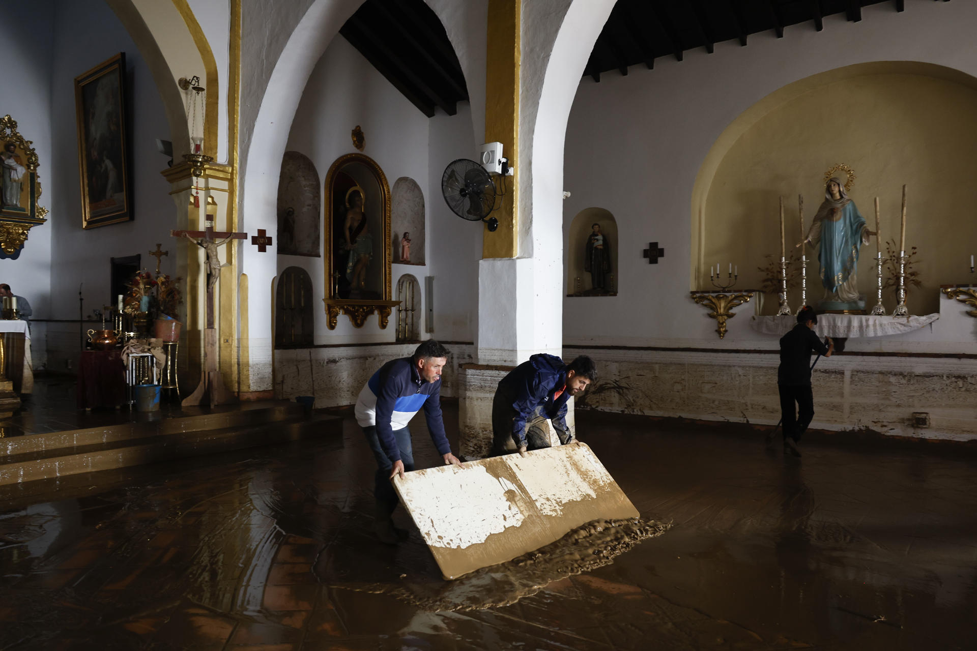 Vecinos colaboran con las labores de limpieza de la Iglesia de la Encarnación en la localidad malagueña de Benamargosa este jueves. EFE/ Jorge Zapata
