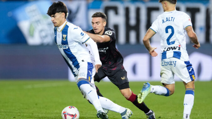 El centrocampista del Leganés Juan Cruz (i) juega un balón ante Adriá Pedrosa (c), del Sevilla, durante el partido de LaLiga que UD Leganés y Sevilla FC disputaron en el estadio de Butarque. EFE/Borja Sánchez-Trillo
