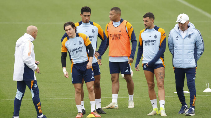 -El entrenador italiano del Real Madrid Carlo Ancelotti (d), el delantero brasileño francés Kylian Mbappé (3d), y el centrocampista ingés Jude Bellingham (3i), este viernes durante el entrenamiento en la Ciudad Deportiva de Valdebebas.-EFE/ Mariscal
