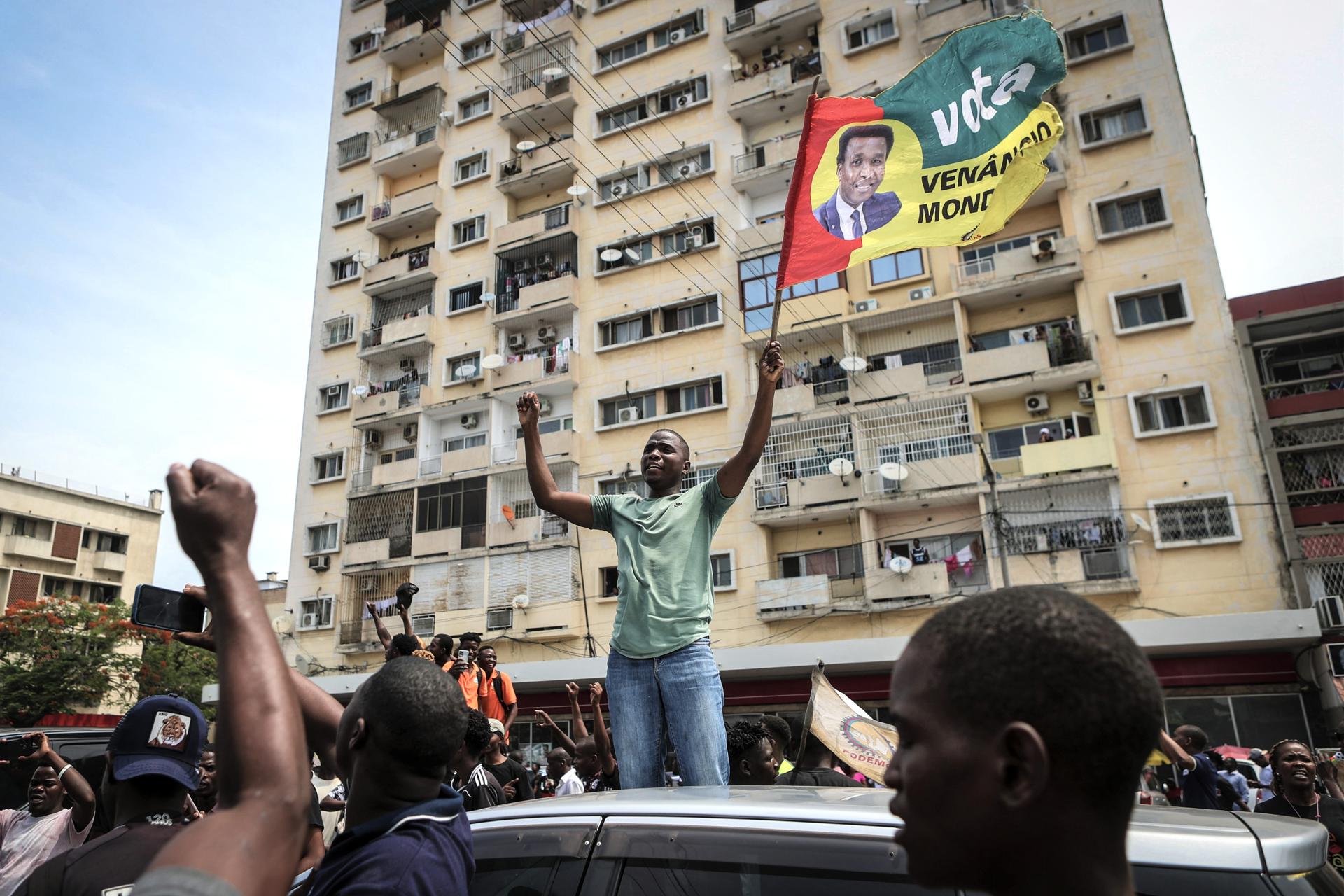 Un manifestante grita consignas mientras agita una bandera que retrata al líder opositor Venancio Mondlane durante una protesta de sus seguidores contra los resultados de las elecciones presidenciales en el centro de Maputo, Mozambique, 22 de noviembre de 2024. La policía mozambiqueña utilizó gas lacrimógeno para dispersar a cientos de manifestantes y simpatizantes del ex candidato presidencial Venancio Mondlane, quien se encuentra actualmente en el exilio, mientras cantaban el himno nacional de rodillas y cuestionaban los resultados de las disputadas elecciones generales celebradas en octubre de 2024. (Elections, Protests) EFE/EPA/LUISA NHANTUMBO
