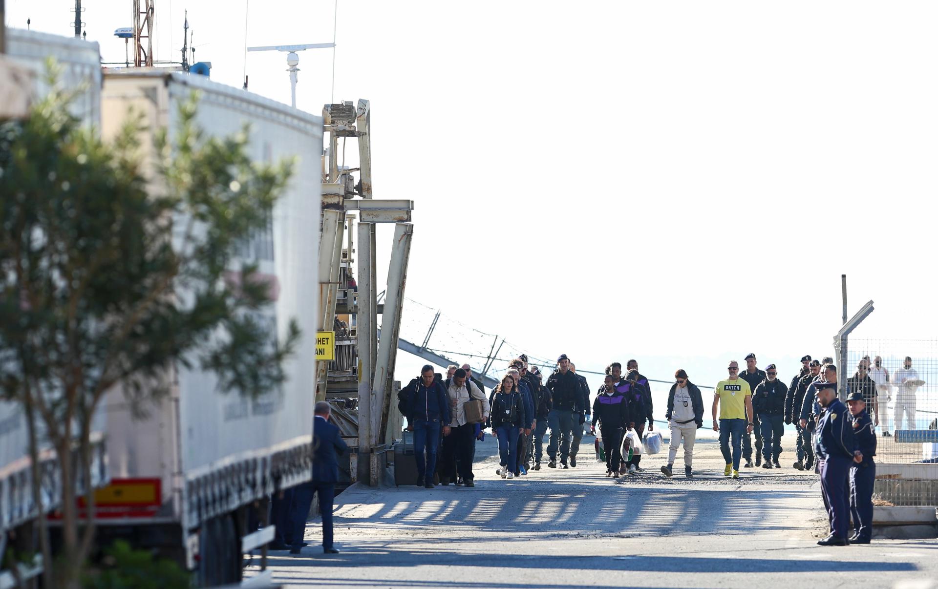 Un grupo de migrantes (C) interceptados en aguas internacionales alrededor de Italia desembarcan del buque de la Marina Italiana Libra en Shengjin, Albania, 08 de noviembre de 2024. Italia ha enviado un grupo de 8 migrantes a Albania, después de que un grupo anterior fuera rechazado en octubre por no pasar el proceso de selección, en un plan destinado a disuadir los peligrosos cruces marítimos al procesar las solicitudes de asilo fuera de la UE. La iniciativa enfrentó retrocesos legales después de que los tribunales italianos dictaminaran que los migrantes no podían ser retenidos en Albania debido a preocupaciones sobre su estatus legal. En respuesta, el gobierno italiano ajustó el marco legal, con la esperanza de que esto fortaleciera la política, que permite alojar temporalmente a hasta 3,000 hombres no vulnerables en instalaciones gestionadas por Italia en Albania. (Italia) EFE/EPA/MALTON DIBRA
