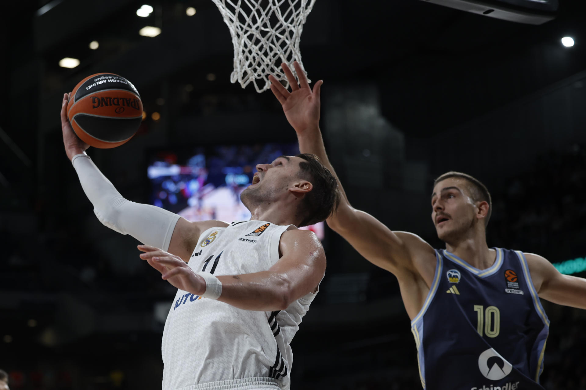 El alero del Real Madrid Mario Hezonja (i) entra a canasta ante Tim Schneider, del Alba Berlín, durante el partido de la Euroliga de baloncesto ante el Real Madrid que disputan este jueves en el Wizink Center. EFE/Juanjo Martin
