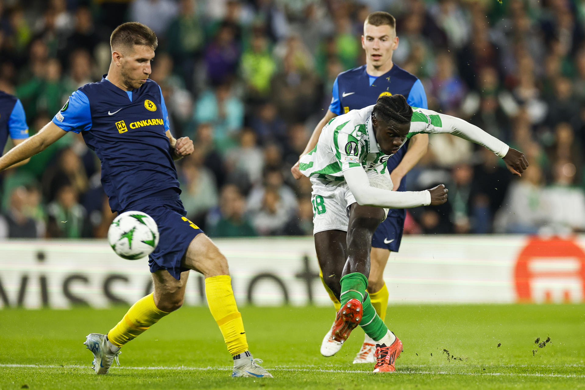 El delantero español del Betis Assane Diao (d) disputa un balón con el defensa esloveno del Celje Damjan Vuklišević (i) durante un encuentro correspondiente a la jornada 3 de la Liga Conferencia disputado entre el Betis y el Celje esloveno en el Benito Villamarín de Sevilla, este jueves. EFE/ Julio Muñoz
