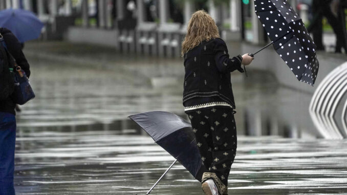 Una mujer se intenta proteger de la fuerte lluvia y el viento con un paraguas, en una imagen de archivo. EFE/Paco Paredes
