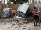 Dos vecinos se abrazan a la entrada de un garaje en Paiporta, Valencia, tras el paso de la DANA. EFE/Biel Aliño