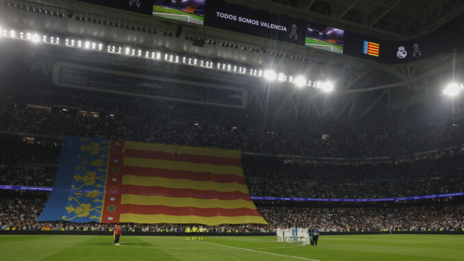 Los jugadores del Real Madrid (d) y del Milán ante la bandera valenciana, antes del partido de la Liga de Campeones que Real Madrid y AC Milán disputan este martes en el estadio Santiago Bernabéu. EFE/Juanjo Martín
