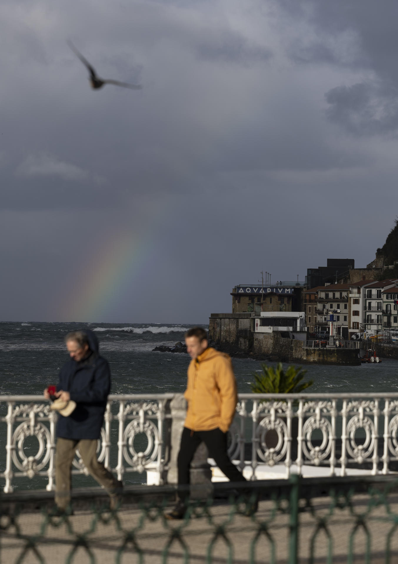 Turistas observan el arco iris en la playa de la Concha de San Sebastián. EFE/Juan Herrero
