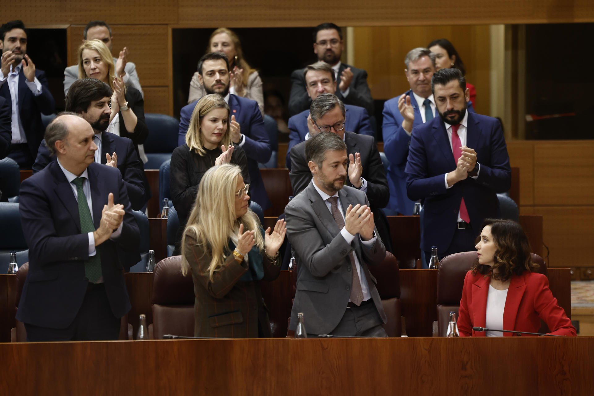 La presidenta de la comunidad de Madrid, Isabel Díaz Ayuso (d), recibe el aplauso de los diputados de su partido (PP) después de una de sus intervenciones durante el pleno de la Asamblea de Madrid este jueves. EFE/Sergio Pérez
