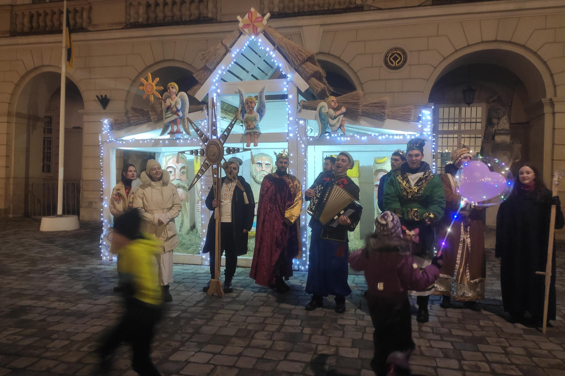 Petro Datskiv (4i) junto con otros miembros de un "vertep" de Lviv -una recreación tradicional de un belén- cantan villancicos en el centro de Leópolis antes de su viaje a las zonas del frente en el este, donde van a actuar ante los soldados y llevarles diverso material muy necesario gracias a las donaciones de los oyentes. EFE/ Rostyslav Averchuk
