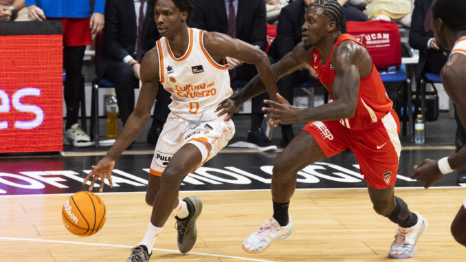 El escolta senegalés de Valencia Basket Brancou Badio (i) controla el balón ante la presión del base estadounidense de UCAM Murcia Dylan Ennis (d), durante el partido de la décimo primera jornada de la liga Endesa jugado en el Palacio de los Deportes de Murcia. EFE/Marcial Guillén
