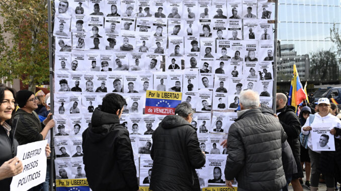 Un cartel muestra fotografías de presos políticos en Venezuela durante la manifestación de opositores políticos venezolanos que ha tenido lugar este domingo en Madrid.EFE/ Victor Lerena
