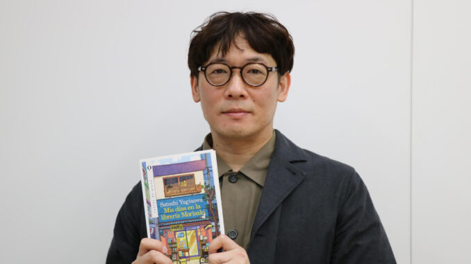 - El autor nipón Satoshi Yagisawa posa con su libro 'Mis días en la librería Morisaki', un éxito editorial representante de la llamada 'cozy fiction' o literatura "amable" japonesa, que se caracteriza por tramas que transmiten paz y seguridad y con abundancia de café y gatos. EFE/ Sara Rodríguez Pachón
