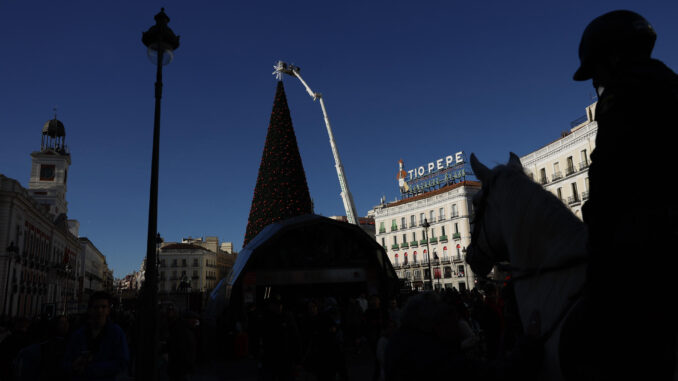 Operarios ponen a punto la estrella que corona el árbol de Navidad en la Puerta del Sol en Madrid, este soleado lunes. EFE/ Mariscal
