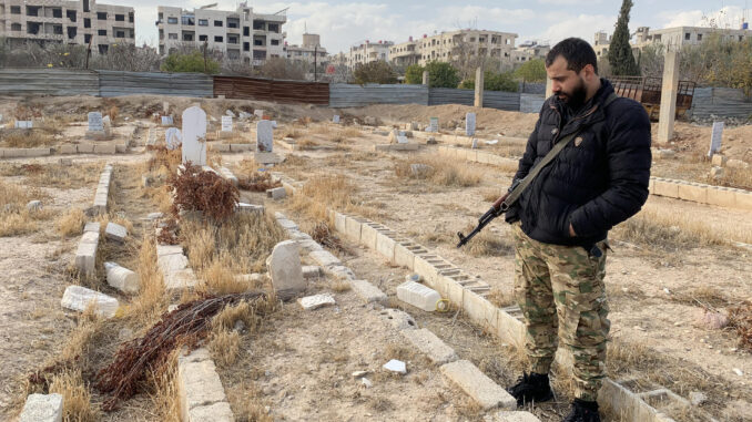 El combatiente Saif el Din al Dahla frente a la tumba de sus familiares muertos en el ataque químico de 2013 en Zamalka, a las afueras de Damasco, el 26 de diciembre de 2024. Para muchos combatientes rebeldes, la caída del régimen de Bachar al Asad supuso una oportunidad de volver a casa por primera vez en mucho tiempo. Para Saif el Din al Dahla, ha marcado un "muy difícil" regreso al lugar donde toda su familia perdió la vida en un ataque químico el 21 de agosto de 2013. 
EFE/Noemí Jabois
