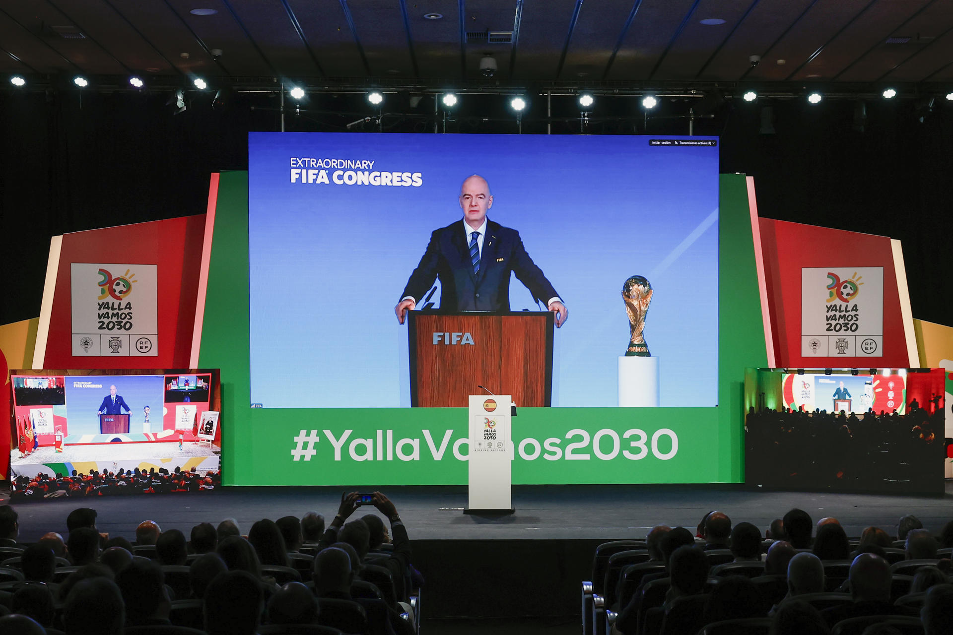 Asistentes al evento observan la intervención del presidente de la FIFA, Gianni Infantino, durante el acto abierto a medios en el que se sigue en directo, con la presencia de diversas autoridades, la reunión del Congreso de FIFA en la que se decide sobre la candidatura conjunta entre Marruecos, Portugal y España - YallaVamos2030 para organizar la Copa del Mundo de fútbol. EFE/ Sergio Pére
