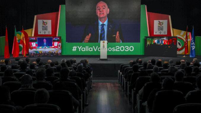 Asistentes al acto observan la intervención del presidente de la FIFA, Gianni Infantino, durante el acto abierto a medios en el que se sigue en directo, con la presencia de diversas autoridades, la reunión del Congreso de FIFA en la que se decide sobre la candidatura conjunta entre Marruecos, Portugal y España - YallaVamos2030 para organizar la Copa del Mundo de fútbol. EFE/ Sergio Pérez
