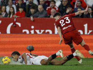 Loïc Badé (i), defensa francés del Sevilla, cae al terreno de juego ante Raúl García, en el estadio Sánchez Pizjuán en foto de archivo de Julio Muñoz. EFE