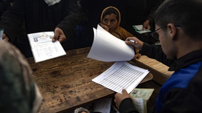 Fotografía de archivo del pasado 3 de diciembre de una niña que espera mientras palestinos hacen fila para recibir ayuda alimentaria en un centro de distribución del Organismo de Obras Públicas y Socorro de las Naciones Unidas para los Refugiados de Palestina en el Cercano Oriente (OOPS) en Khan Younis, en el sur de la Franja de Gaza, el 3 de diciembre de 2024.EFE/EPA/Haitham Imad
