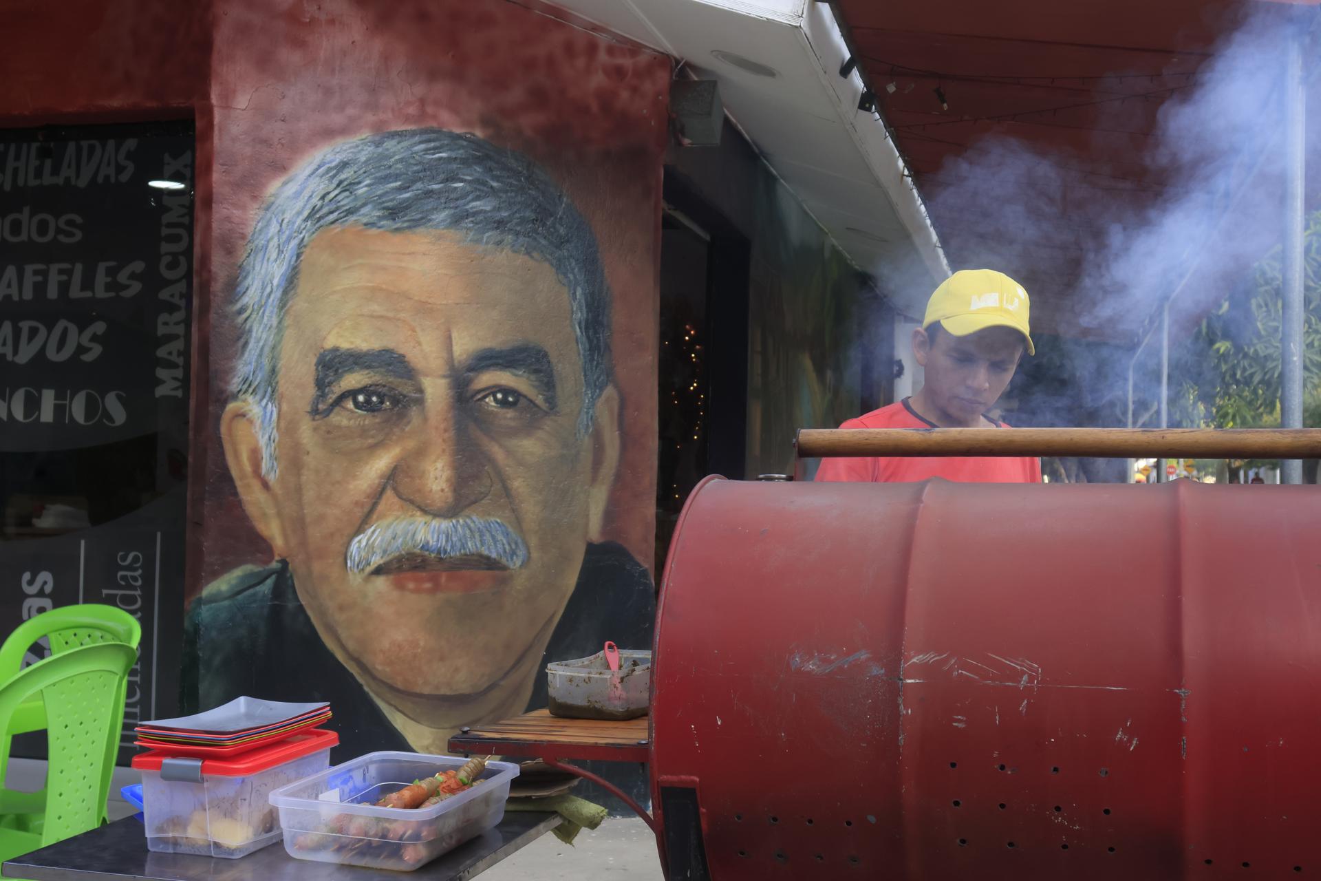 Un hombre cocina frente a un mural con la imagen del escritor Gabriel García Márquez, este miércoles en Aracataca (Colombia). El realismo mágico de Macondo afloró nuevamente en Aracataca, el pueblo del Caribe colombiano donde nació Gabriel García Márquez, nobel de Literatura de 1982, con la proyección en su plaza, y para su gente, del primer episodio de 'Cien años de soledad', la serie de Netflix basada en su novela del mismo nombre. EFE/ Ricardo Maldonado Rozo
