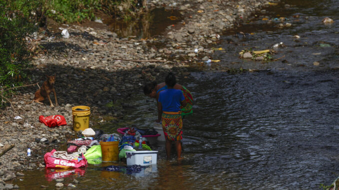 Dos mujeres lavan ropa en un río contaminado con basura, este miércoles en la comunidad de Kuna Nega, en Ciudad de Panamá (Panamá).EFE/ Bienvenido Velasco
