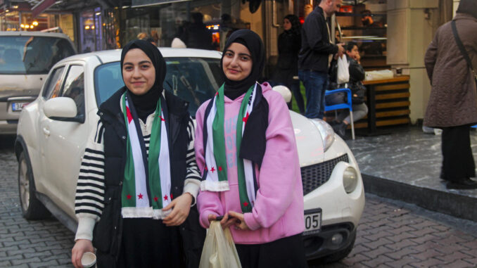 Hay unanimidad en el barrio de Esenyurt, un lugar con una gran comunidad de refugiados sirios en el oeste de Estambul: todos volverán a Siria, "muy pronto", "dentro de dos o tres meses", cuando se haya estabilizado la situación. En la imagen, Nur y Tuqa, dos jóvenes sirias refugiadas, con la bandera 'rebelde' siria, en el barrio de Esenyurt, Estambul, el 11 de diciembre de 2024. EFE/Ilya U. Topper
