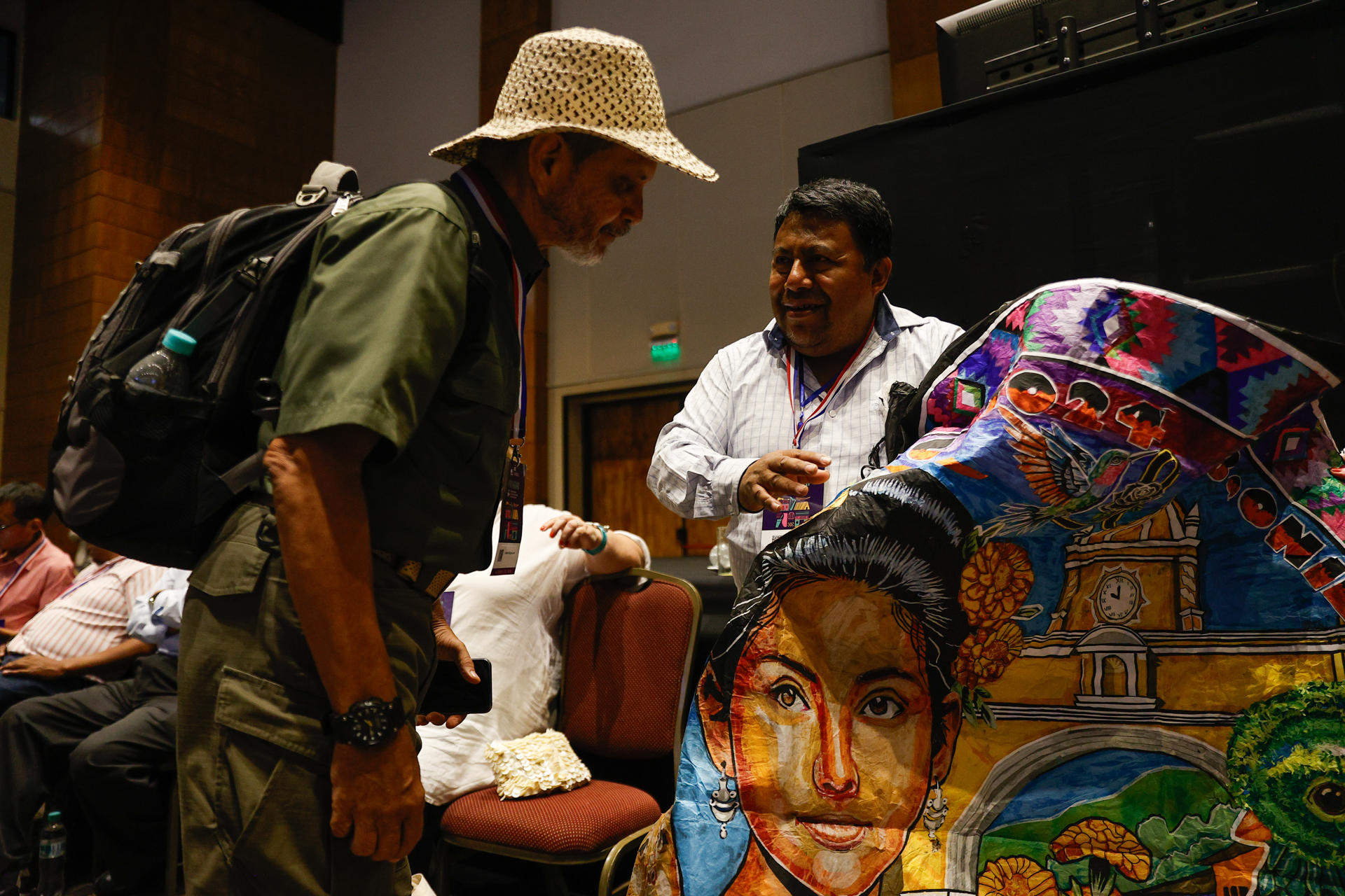 Julio Asturias, artista barrilete guatemalteco, muestra a un visitante sus creaciones durante la decimonovena sesión del Comité Intergubernamental para la Salvaguardia del Patrimonio Cultural Inmaterial de la Organización de las Naciones Unidas para la Educación, la Ciencia y la Cultura (Unesco), este miércoles, en Luque (Paraguay). EFE/ Juan Pablo Pino
