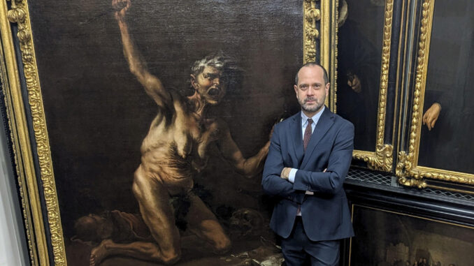 El director de la Galería de los Uffizi, Simone Verde, posa junto a la obra 'La Bruja', considerada la obra maestra de la pintura esotérica del siglo XVII, del artista maldito Salvator Rosa. EFE/ Galeria de los Uffizi
