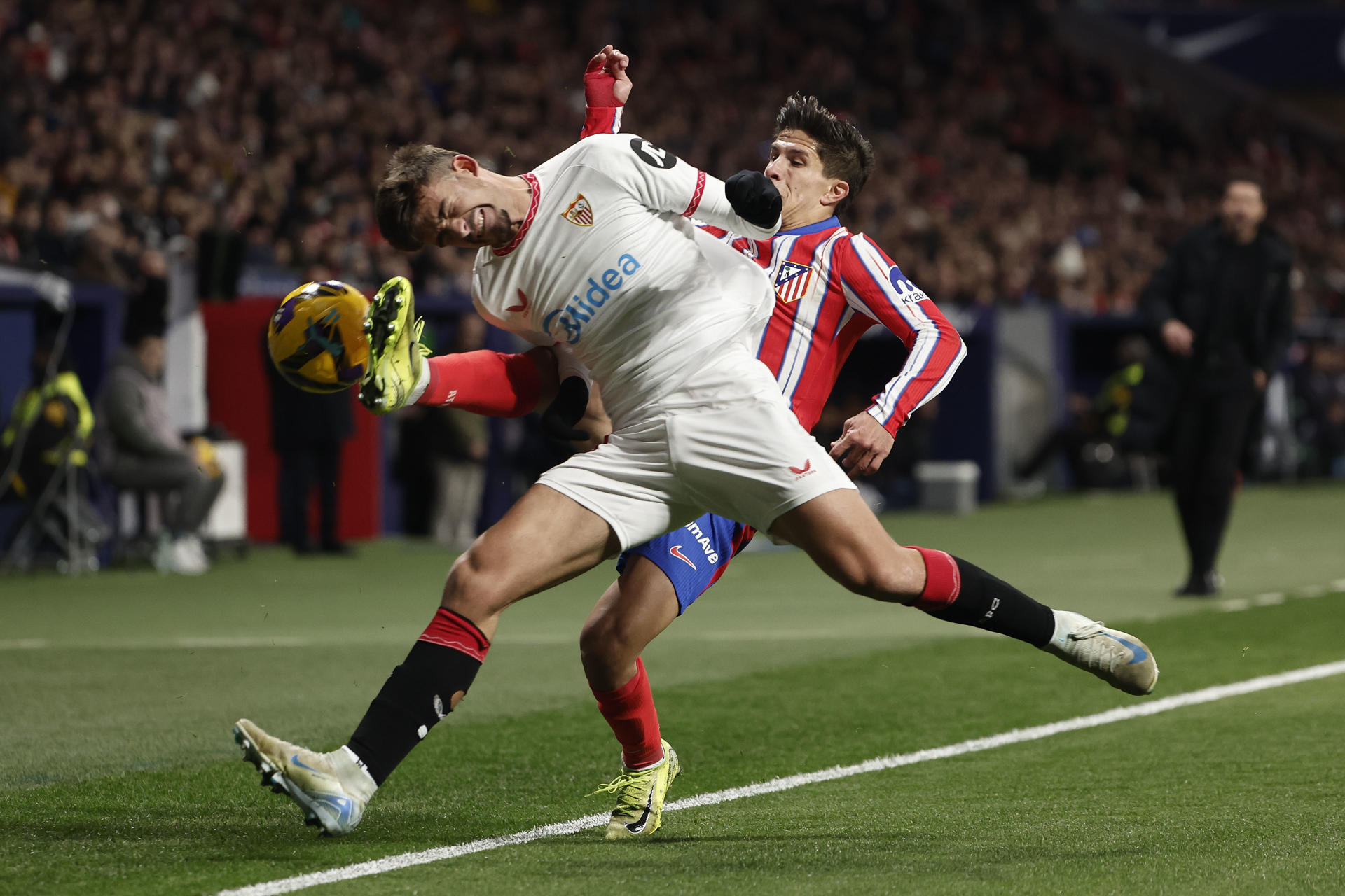 El delantero argentino del Atlético de Madrid Giuliano Simeone (d) disputa un balón ante el defensa del Sevilla Kike este domingo, durante el partido de la jornada 16 de LaLiga EA Sports, entre el Atlético de Madrid y el Sevilla, en el estadio Metropolitano, en Madrid. EFE/ Sergio Pérez
