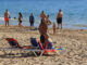 Varias personas disfrutan del buen tiempo en la Playa de Levante, en Benidorm, en la víspera de Nochebuena. EFE/Morell