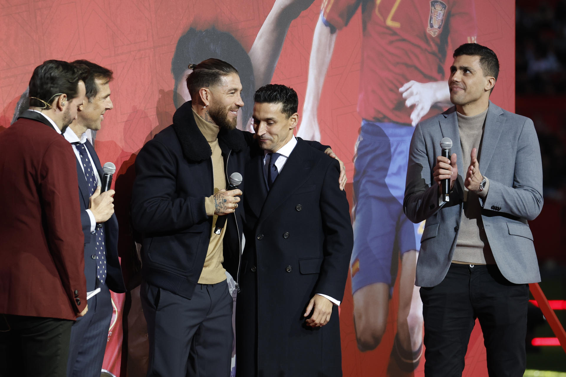 Sergio Ramos (3i), abraza a Jesús Navas, junto a Rodri (d), durante el homenaje al de Los Palacios, leyenda del fútbol español que el 22 de diciembre puso fin, con 39 años, a su exitosa carrera tras disputar 989 partidos como profesional en los que ganó un Mundial, dos Eurocopas y una Liga de Naciones con la selección, además de ocho títulos con el Sevilla y tres con el Manchester City, este lunes en el estadio Sánchez Pizjuán de la capital hispalense. EFE/Julio Muñoz
