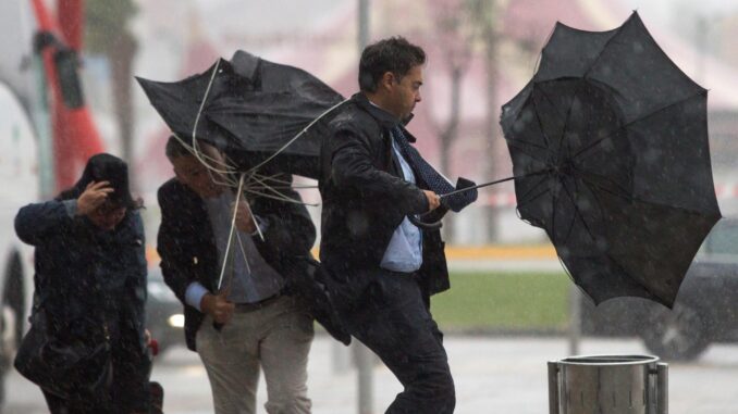 En la imagen de archivo, varias personas sujetan sus paraguas intentando que no se les vuelen debido al fuerte viento y a la lluvia en Málaga. EFE/Daniel Pérez
