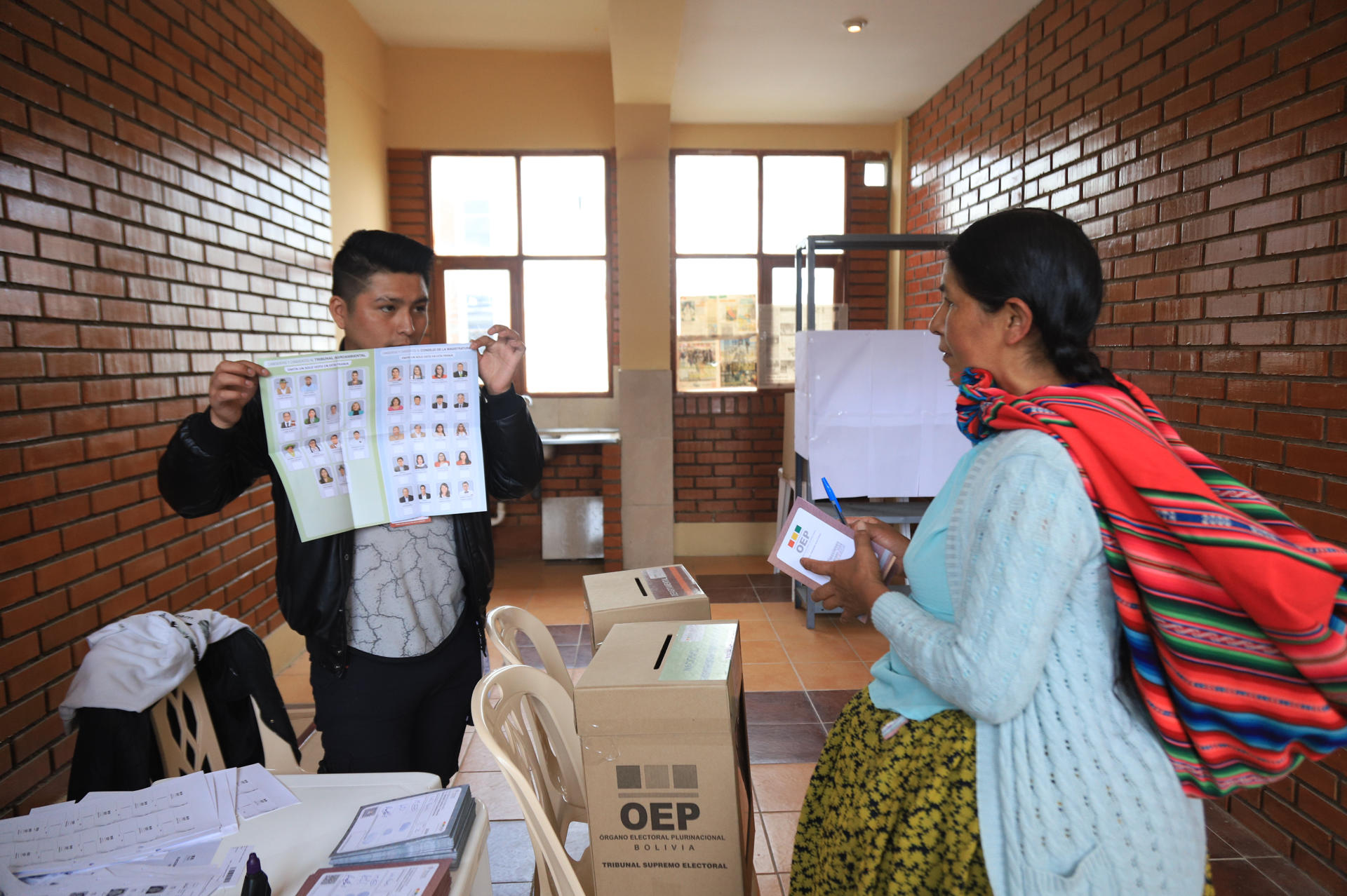 Un jurado electoral muestra una papeleta vacía a una mujer aimara en la jornada electoral de elecciones judiciales este domingo, en La Paz (Bolivia). EFE/ Gabriel Márquez.
