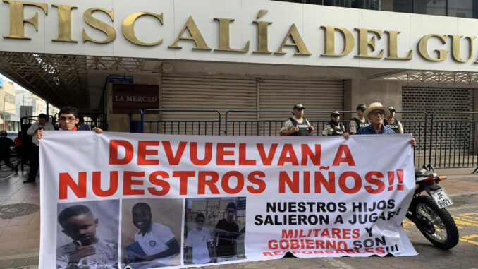 Luis Arroyo (d) y Josué Arroyo (i), padre y hermano de un menor desaparecido, sostienen un cartel con la foto de sus familiares en los exteriores de la Fiscalía Provincial del Guayas en Guayaquil (Ecuador). EFE/Cristina Bazán
