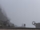 Paseantes caminan entre las esculturas del Peine del Viento de San Sebastián que este viernes han amanecido cubiertas por una densa niebla. EFE/Juan Herrero.